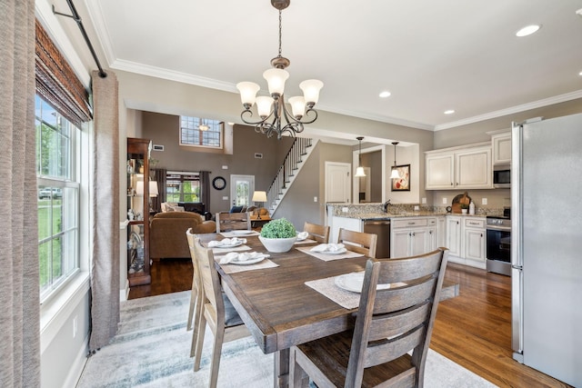 dining room with an inviting chandelier, ornamental molding, light wood-style floors, and stairway