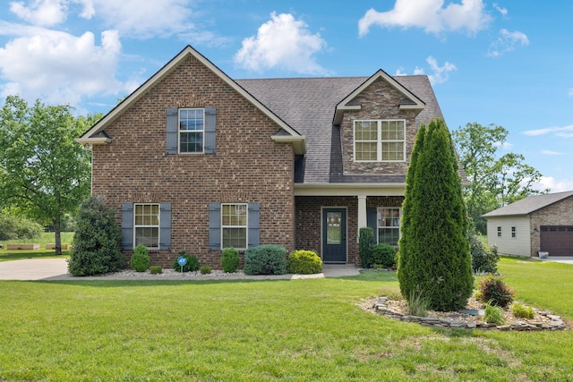 view of front facade with a shingled roof, a front lawn, and brick siding