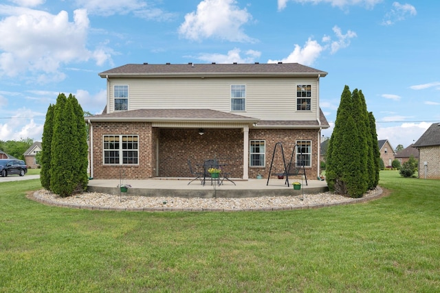 rear view of property featuring brick siding, a patio, and a yard