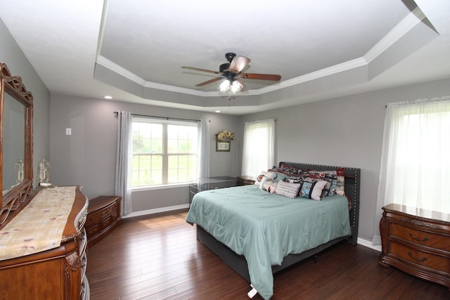 bedroom with crown molding, baseboards, a tray ceiling, and dark wood-style floors