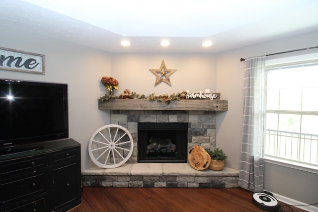 living room with recessed lighting, a stone fireplace, and wood finished floors