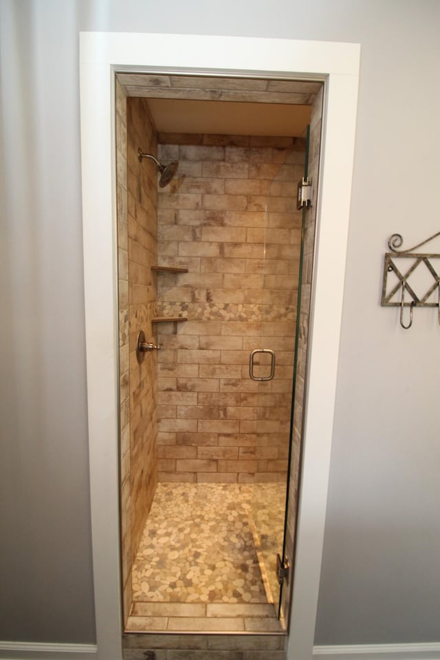 bathroom with baseboards and a shower stall