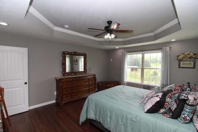 bedroom featuring baseboards, ornamental molding, wood finished floors, and a tray ceiling