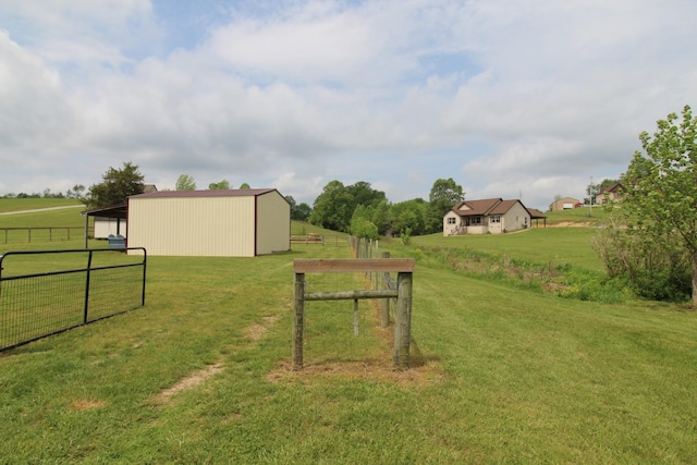 view of yard featuring a pole building, fence, an outbuilding, and a rural view