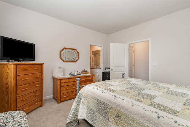 bedroom featuring baseboards, ensuite bathroom, and light carpet