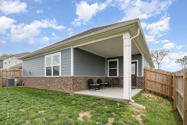 back of house with fence, cooling unit, brick siding, a patio area, and a lawn