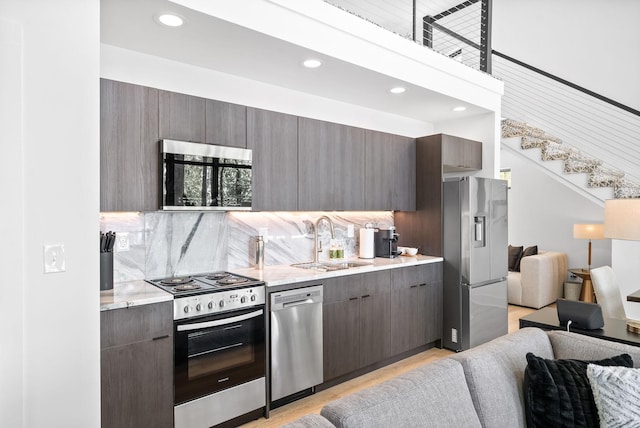 kitchen featuring open floor plan, recessed lighting, tasteful backsplash, a sink, and appliances with stainless steel finishes
