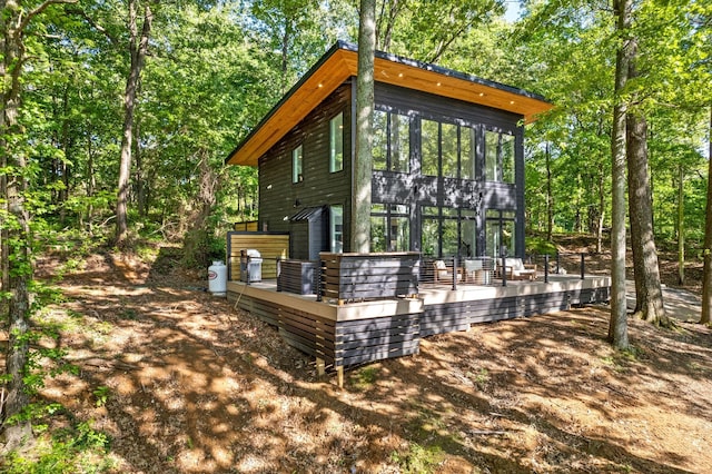 view of side of home featuring a sunroom and a deck