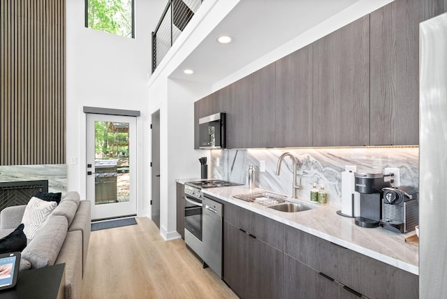 kitchen with light wood-type flooring, a sink, modern cabinets, and stainless steel appliances
