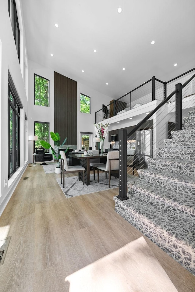 living area featuring visible vents, a high ceiling, wood finished floors, and recessed lighting