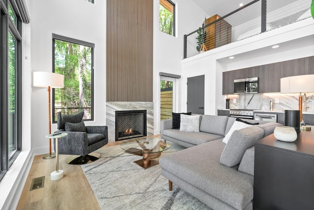 living room with visible vents, a towering ceiling, wood finished floors, and a fireplace