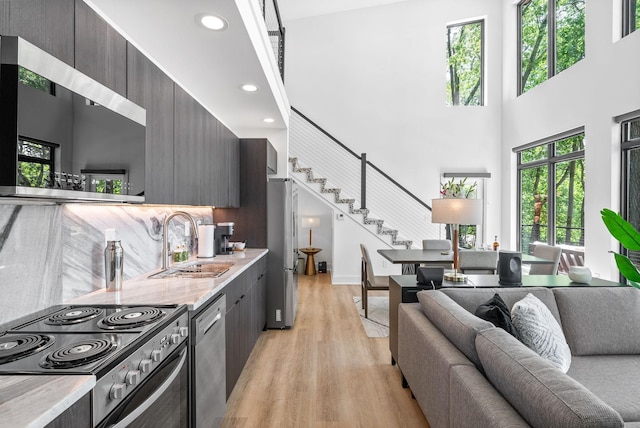 interior space featuring light wood-type flooring, plenty of natural light, stairway, and a towering ceiling