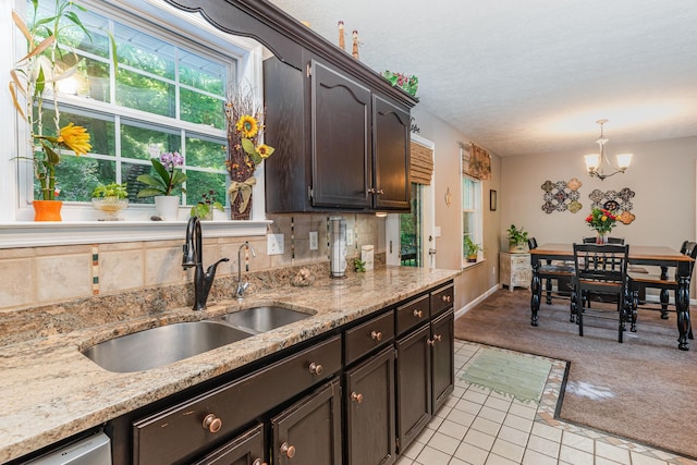 kitchen with light colored carpet, a sink, light tile patterned floors, and dark brown cabinetry