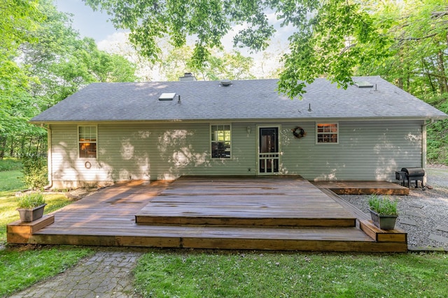 rear view of house with a deck, a chimney, and a shingled roof