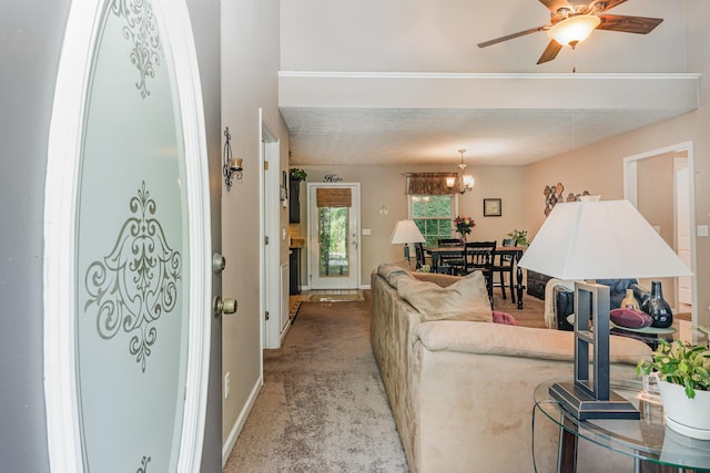 living room with baseboards, ceiling fan with notable chandelier, and light colored carpet