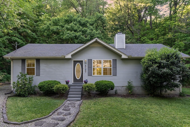 ranch-style home with a chimney, roof with shingles, and a front lawn