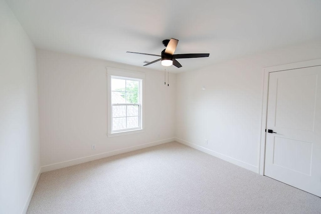 empty room with ceiling fan, light colored carpet, and baseboards