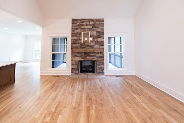 unfurnished living room featuring light wood-style flooring, vaulted ceiling, and a fireplace