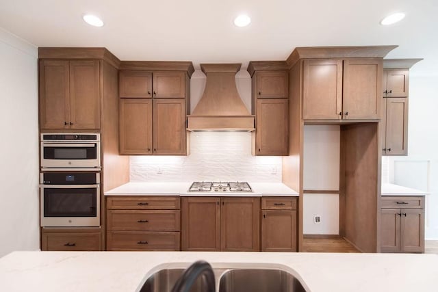kitchen with decorative backsplash, appliances with stainless steel finishes, light countertops, custom exhaust hood, and recessed lighting