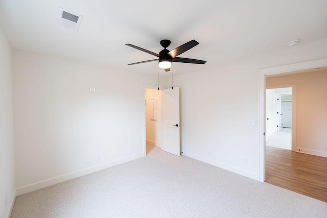 carpeted spare room featuring visible vents, a ceiling fan, and baseboards