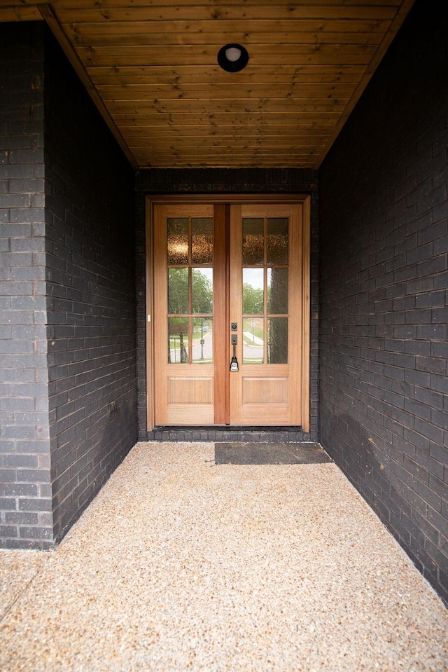 property entrance featuring brick siding and french doors
