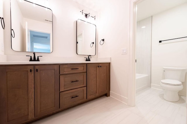 full bath featuring baseboards, a sink, double vanity, and toilet