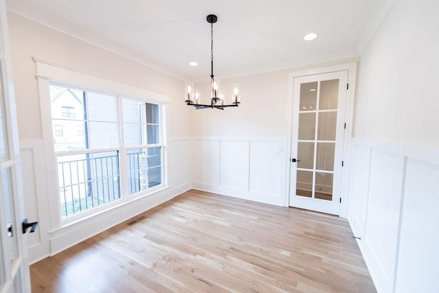 unfurnished dining area with an inviting chandelier, a healthy amount of sunlight, and a decorative wall