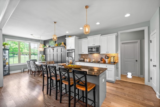 1005 Felts Dr, Clarksville, TN 37043 - kitchen featuring a kitchen island with sink, a kitchen bar, appliances with stainless steel finishes, tasteful backsplash, and baseboards