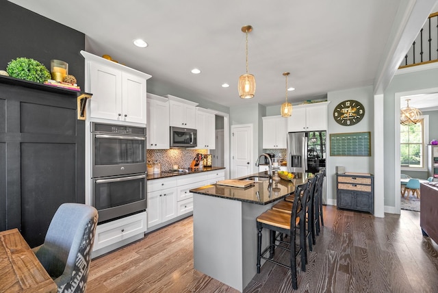 1005 Felts Dr, Clarksville, TN 37043 - kitchen with a sink, a kitchen breakfast bar, stainless steel appliances, white cabinetry, and decorative backsplash