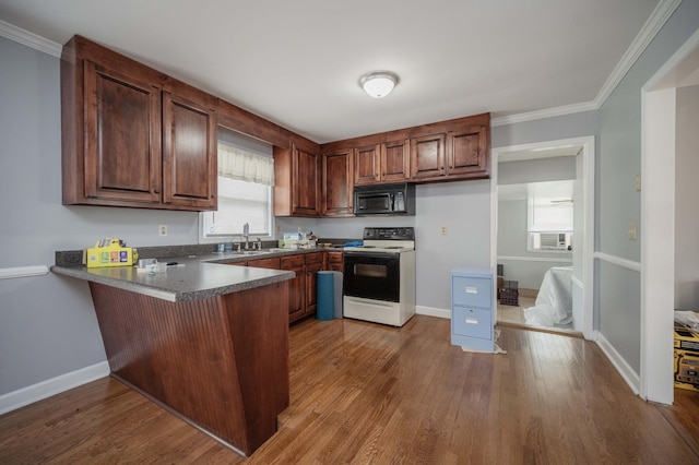 kitchen featuring a sink, a peninsula, black microwave, dark countertops, and electric stove