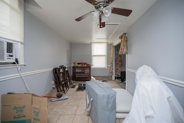 interior space with a ceiling fan, light tile patterned floors, attic access, and cooling unit