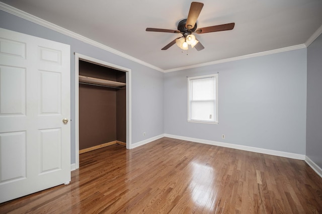 unfurnished bedroom featuring ceiling fan, wood finished floors, baseboards, a closet, and ornamental molding