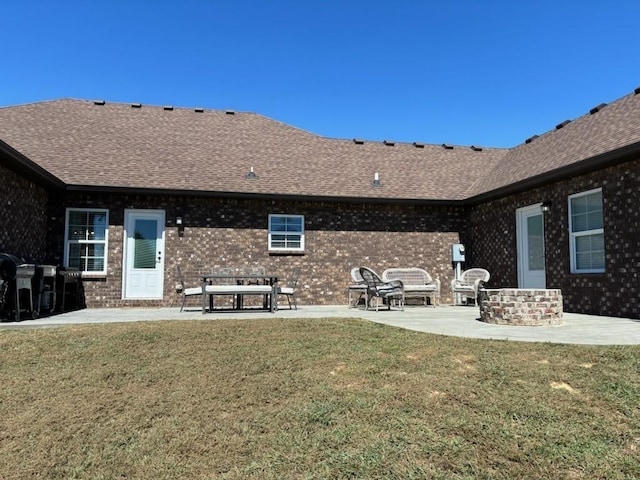 rear view of house with a patio, a lawn, roof with shingles, and brick siding