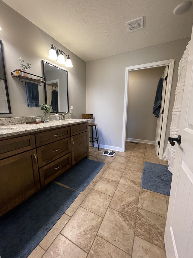 full bathroom with vanity, baseboards, a textured ceiling, and visible vents