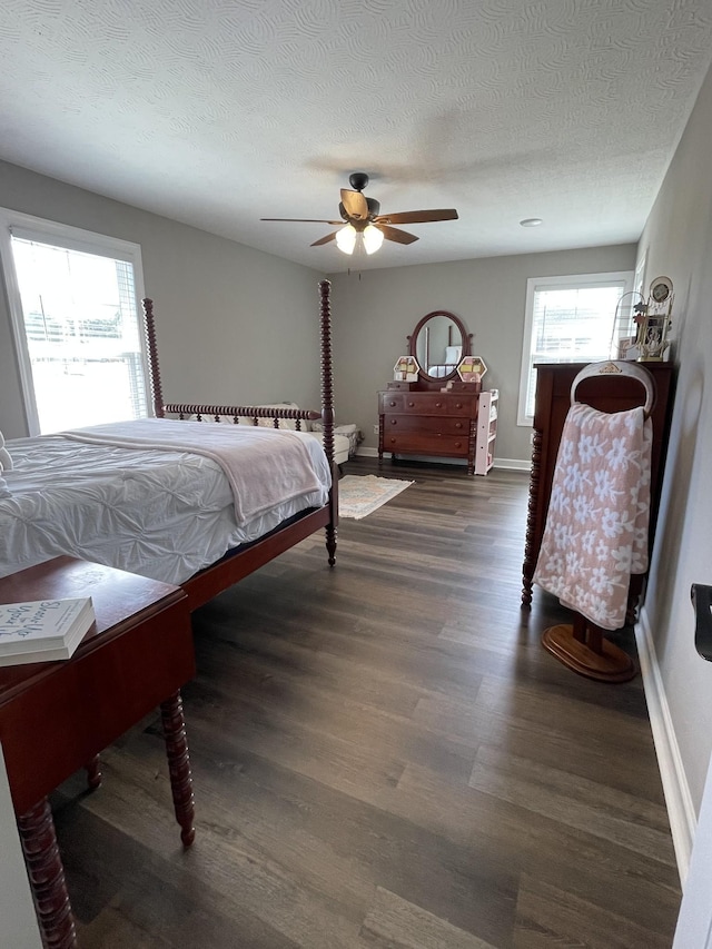 bedroom featuring a ceiling fan, baseboards, dark wood finished floors, and a textured ceiling