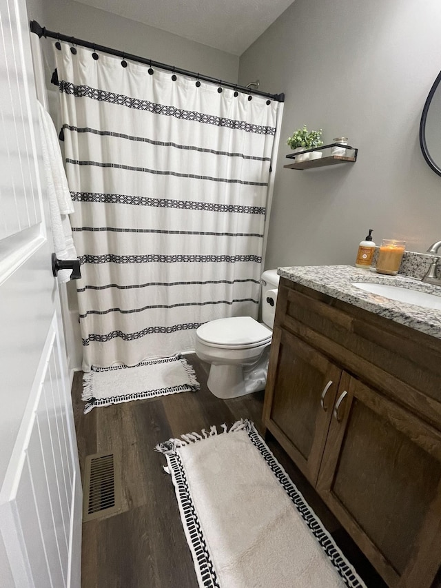 full bathroom featuring visible vents, vanity, curtained shower, wood finished floors, and toilet