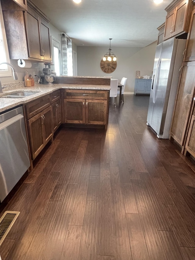 kitchen with dark wood-style flooring, visible vents, a sink, a peninsula, and stainless steel appliances