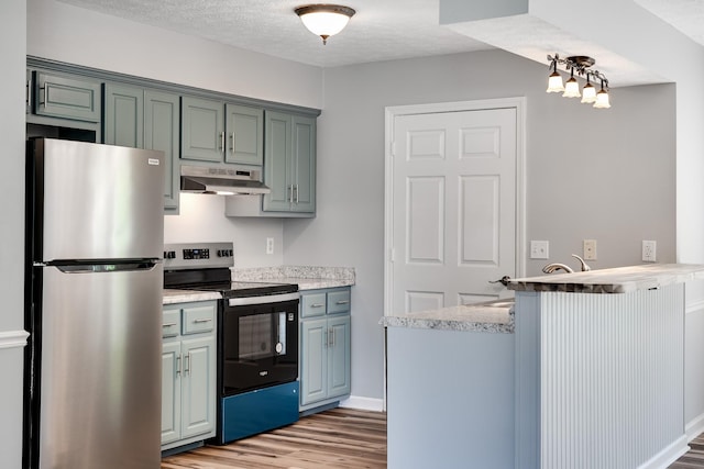 kitchen featuring electric range oven, freestanding refrigerator, a peninsula, light wood finished floors, and under cabinet range hood