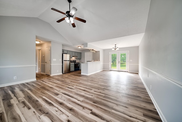 unfurnished living room with french doors, ceiling fan with notable chandelier, lofted ceiling, and wood finished floors