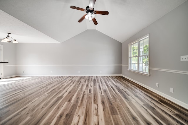 unfurnished living room with baseboards, vaulted ceiling, wood finished floors, and ceiling fan with notable chandelier