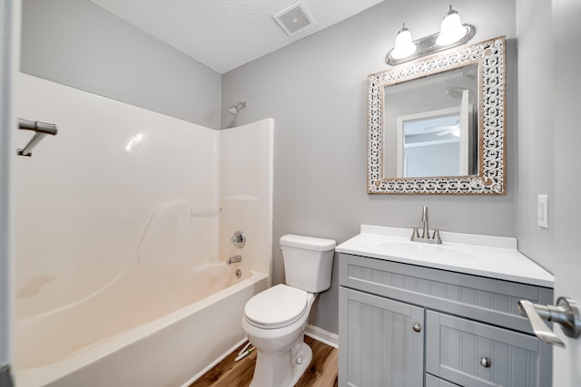 bathroom with visible vents, wood finished floors, shower / washtub combination, vanity, and toilet