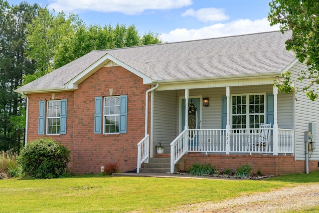 single story home with a porch, brick siding, a shingled roof, and a front yard
