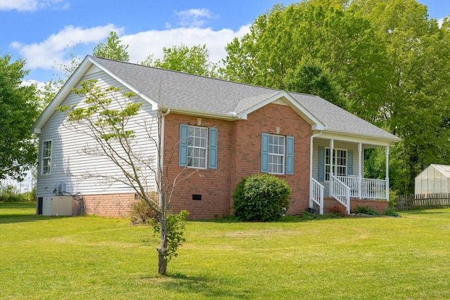 view of side of home with covered porch, a shingled roof, a yard, and crawl space