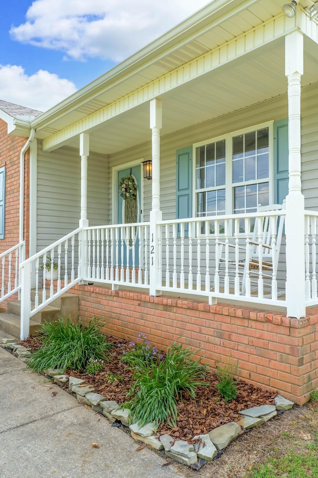 view of exterior entry with covered porch and brick siding