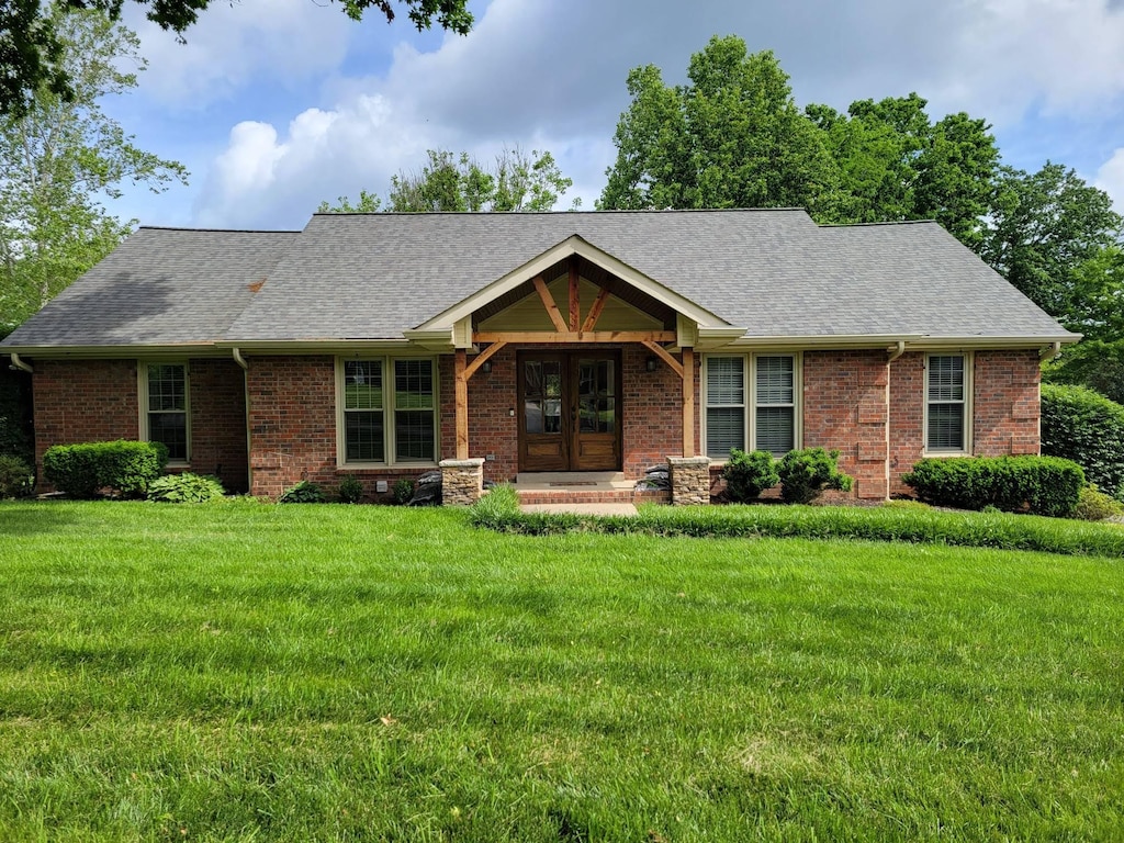 ranch-style house featuring french doors, brick siding, a shingled roof, and a front lawn