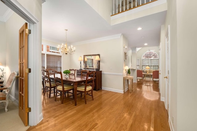 dining space featuring crown molding, light wood-style floors, baseboards, recessed lighting, and a notable chandelier