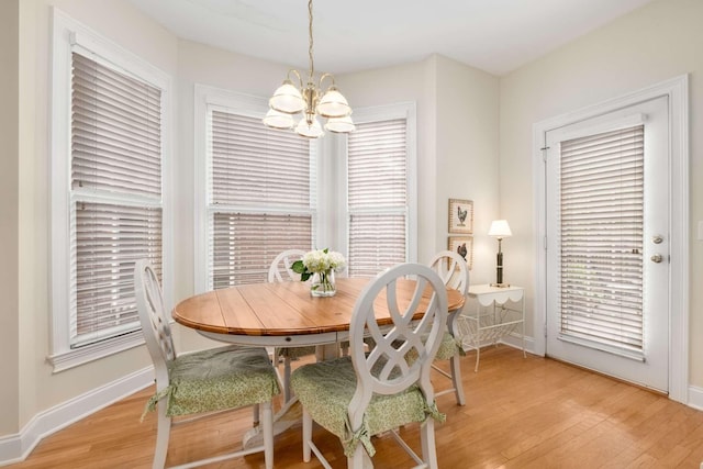 dining space featuring baseboards, a chandelier, and light wood finished floors