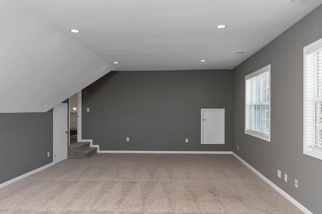 unfurnished living room with recessed lighting, carpet flooring, baseboards, and lofted ceiling