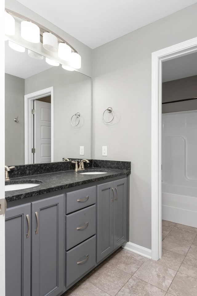 full bathroom with baseboards, double vanity, tile patterned floors, and a sink