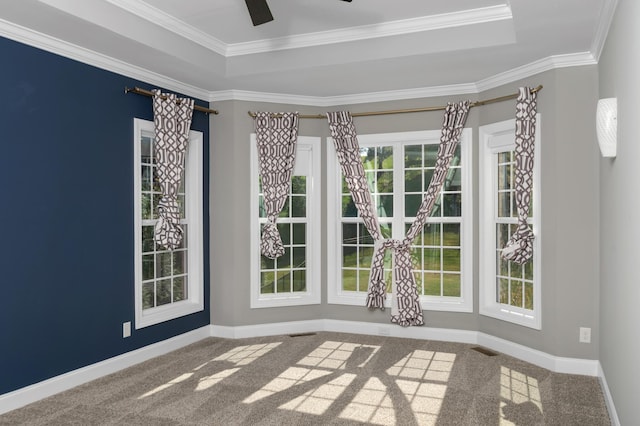 carpeted empty room featuring baseboards, ornamental molding, ceiling fan, and a raised ceiling
